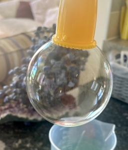 Close-up of a bubble forming at the end of a yellow bubble tube.