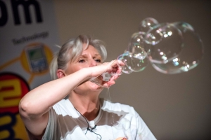 Scientific Sue creating a chain of bubbles using her hands as bubble wands during a live science demonstration