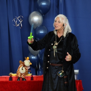 Scientific Sue in wizard-style clothing uses an electro levitation wand to make a lightweight mylar shape float in the air during a show.