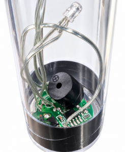 Close-up through the clear light-up stick showing internal wires, an LED, a green circuit board and a small black speaker.